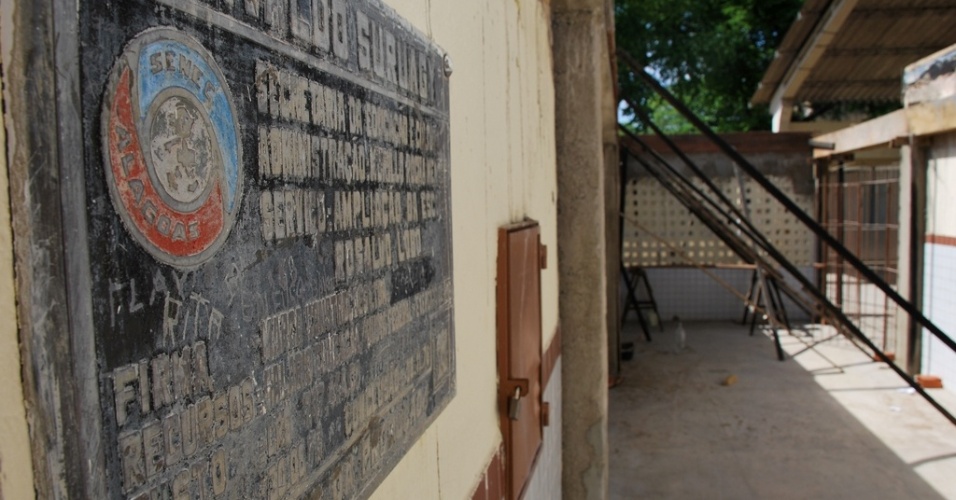 Placa esquecida e chapiscada de uma das ampliações, da Escola Estadual Rosalvo Lôbo, se perde em meio à metralha, tijolos e madeira